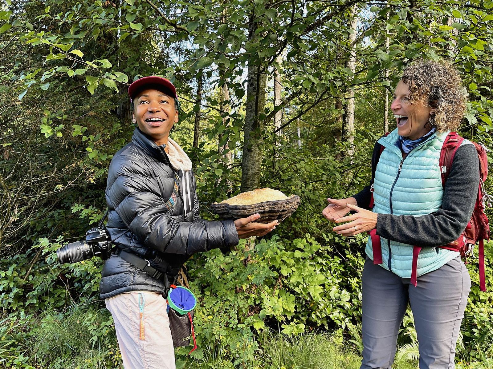 Both naturalists laughing, Genell holding the hoof fungus out to show it.
